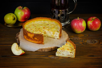 Apple cheesecake on a rustic kitchen with a tea kettle on the wooden dark background