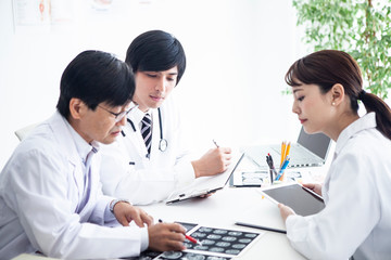 Obraz premium 医者三人が患者の資料をみながら会議を進めている