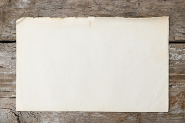 Old and empty sheet of paper on a wooden surface. Vintage and retro background with space for text or image.
