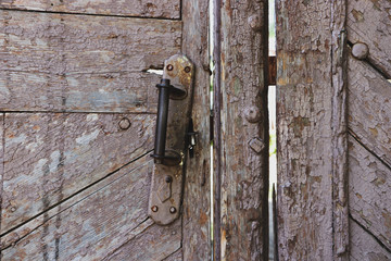 An old wooden gate with a rusty handle. Close-up.