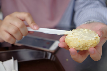 Young muslim woman sweep the clotted cream  on scone at the strawberry farm at Cameron Highland.