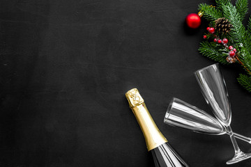 New Year celebration with spruce branch, champagne and glasses black table background top view mock up