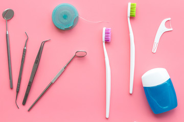 Tooth care with toothbrush, dental floss and dentist instruments. Set of cleaning products for teeth on pink background top view