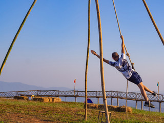 Young man swinging on the top of the hill and enjoying the view.