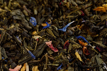 Mix of black tea with green sencha tea and cornflower flowers and strawberry slices.Dry fruit leaf texture background. Macro.