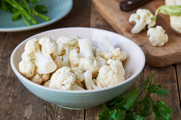 Pieces of raw cauliflower in a bowl on a wooden table