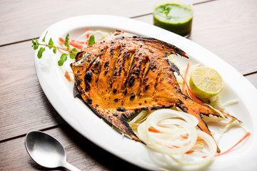 Tandoori Pomfret fish cooked in a clay oven and garnished with lemon , mint, cabbage and carrot salad. Selective focus