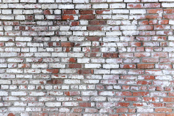 The wall of old red brick covered with white peeling paint. The texture of the brickwork. Grunge background with space for text or image. Empty template and mockup for designers.