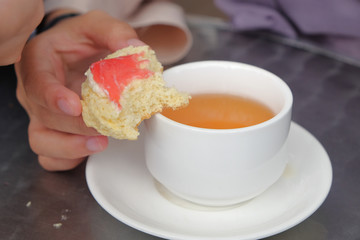 Young muslim woman eating delicious scone with strawberry jam and tea at the strawberry farm at Cameron Highland.