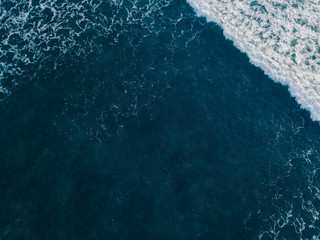 Fototapeta premium Sea aerial view, top view, amazing nature background. Blue of the water and beautiful sand coasline. Azure beach with turquoise waves and clear water of ocean at sunny day. Sea view from flying drone