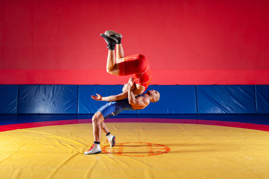 The concept of fair wrestling. Two greco-roman  wrestlers in red and blue uniform wrestling  on a yellow wrestling carpet in the gym