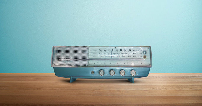 Old antique AM FM stereo radio isolated on wood table with mint blue background .
