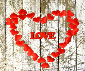 Heart shape from red hearts and the word love on grunge white wooden background. Romantic vintage valentine’s day and wedding background
