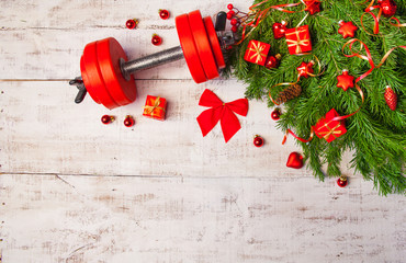 Christmas or New Year on a white background. Composition with dumbbells, gift, red and gold glass balls, fir tree branches for healthy lifestyle and sport