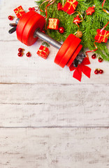 Christmas or New Year on a white background. Composition with dumbbells, gift, red and gold glass balls, fir tree branches for healthy lifestyle and sport