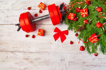 Christmas or New Year on a white background. Composition with dumbbells, gift, red and gold glass balls, fir tree branches for healthy lifestyle and sport