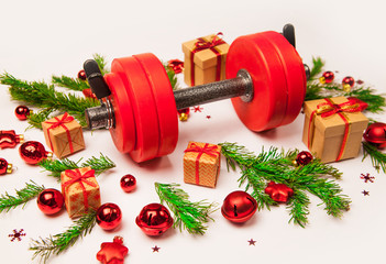 Christmas or New Year on a white background. Composition with dumbbells, gift, red and gold glass balls, fir tree branches for healthy lifestyle and sport