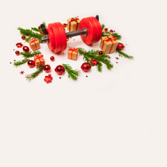 Christmas or New Year on a white background. Composition with dumbbells, gift, red and gold glass balls, fir tree branches for healthy lifestyle and sport