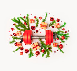 Christmas or New Year on a white background. Composition with dumbbells, gift, red and gold glass balls, fir tree branches for healthy lifestyle and sport