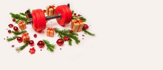 Christmas or New Year on a white background. Composition with dumbbells, gift, red and gold glass balls, fir tree branches for healthy lifestyle and sport