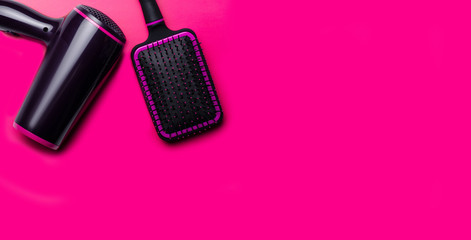 Hair dryer and hairbrush on a pink background