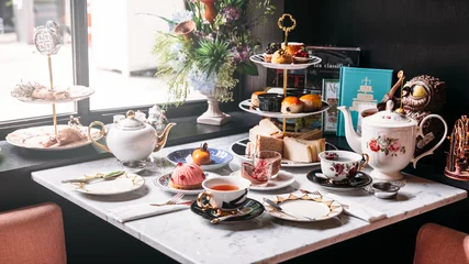 Foto op Plexiglas Thee Engelse afternoon tea-set inclusief hete thee, gebak, scones, sandwiches en minitaarten op marmeren tafel.