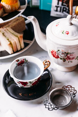 Hot Butterfly Pea Blueberry Tea served in porcelain vintage cup with stainless steel tea strainer...