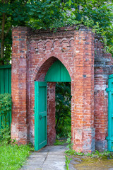 Fototapeta na wymiar open green door in the brick gate