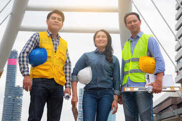 Obraz premium Working engineer. They are standing in town and see sky.They are mean teamwork and spirit beside building background. Photo concept for engineering and team work.