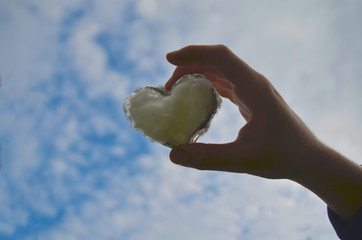 Man hold hand up to sky in the shape of love heart with heart on nature sunlight flare and cloud.