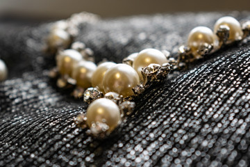 Women's metal jewelry made of pearls. Silver accessory for girls on a silver fabric background,...