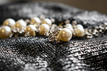 Women's metal jewelry made of pearls. Silver accessory for girls on a silver fabric background,...