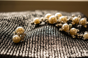 Women's metal jewelry made of pearls. Silver accessory for girls on a silver fabric background,...