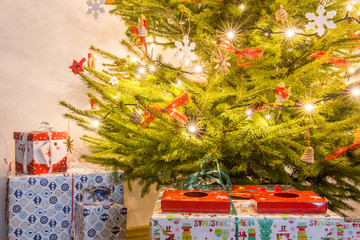 Boże Narodzenie - zdobiona, świąteczna choinka z lampkami i kolorowymi prezentami