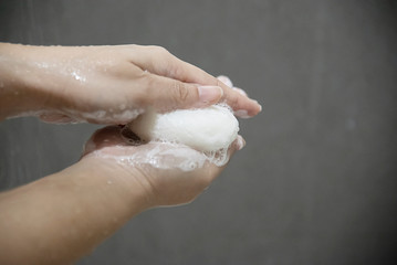Lady hands with soap in a bath room - body health care concept