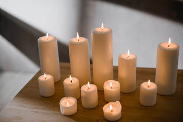 Fototapeta na wymiar A group of different sized candles stands on a simple wooden table.
