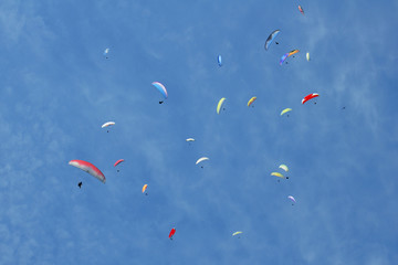 Paragliders are circling in an ascending current above the mountain Sarangkot. Blue sky, multi-colored wings.