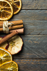 Hot winter holiday beverage aroma ingredients. Dried orange apple slices cinnamon sticks on old plank wood background. New year Christmas decoration elements. Vintage style copy space