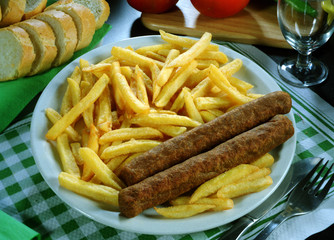 Plato combinado de dos salchichas de tipo aleman y patatas fritas.