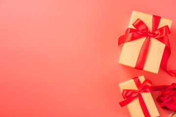 Gift box with red ribbon and rose in trendy color of 2019 living coral, concept of Valentine's, anniversary, mother's day, copy space, top view.