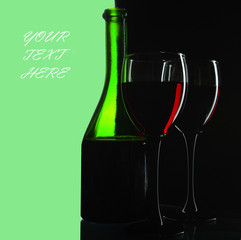 Two glasses with red wine and a green bottle on a dark background. Copy space