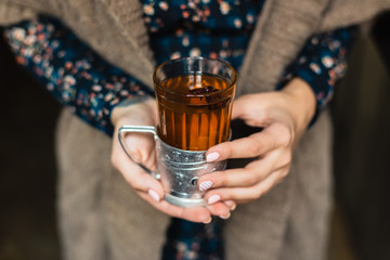 A glass with hot grog in woman's hands - obrazy, fototapety, plakaty