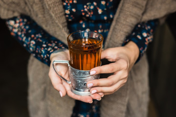 A glass with hot grog in woman's hands