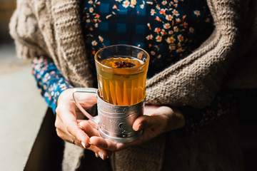 A glass with hot grog in woman's hands