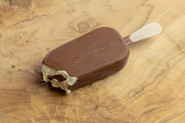 Angebissenes eis am stiel auf einem Holzhintergrund