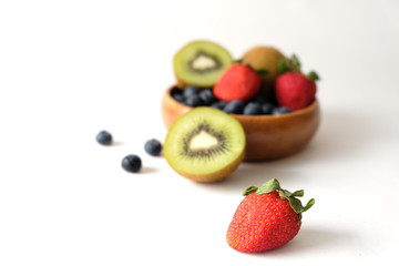 The fruit is placed in a brown wooden bowl on a white table.