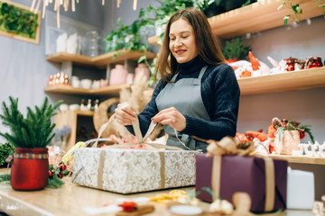 Female person ties a gold bow on gift box