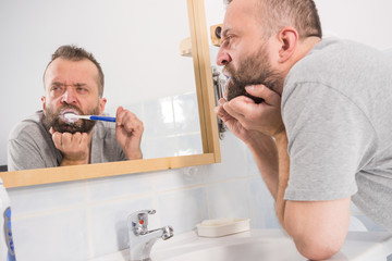 Fototapeta premium Bored guy brushing his teeth in bathroom