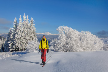 Fototapeta na wymiar tourist in outdoors clothes is riding on wooden skis in beautiful snowy Carpathian mountains. Ukraine