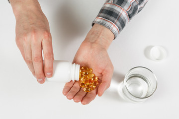 Obraz premium Man hand holds yellow medication capsules of omega 3